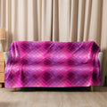 Luxurious pink plaid sherpa blanket draped over a couch, offering a cozy and stylish winter touch to your living room.