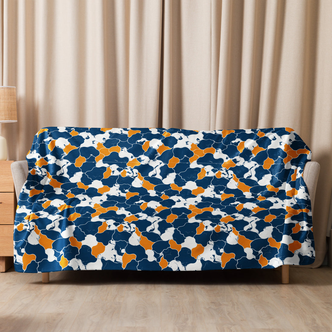 Navy, orange, and white kaleidoscope patterned sherpa blanket on a sofa, showcasing vibrant winter design.