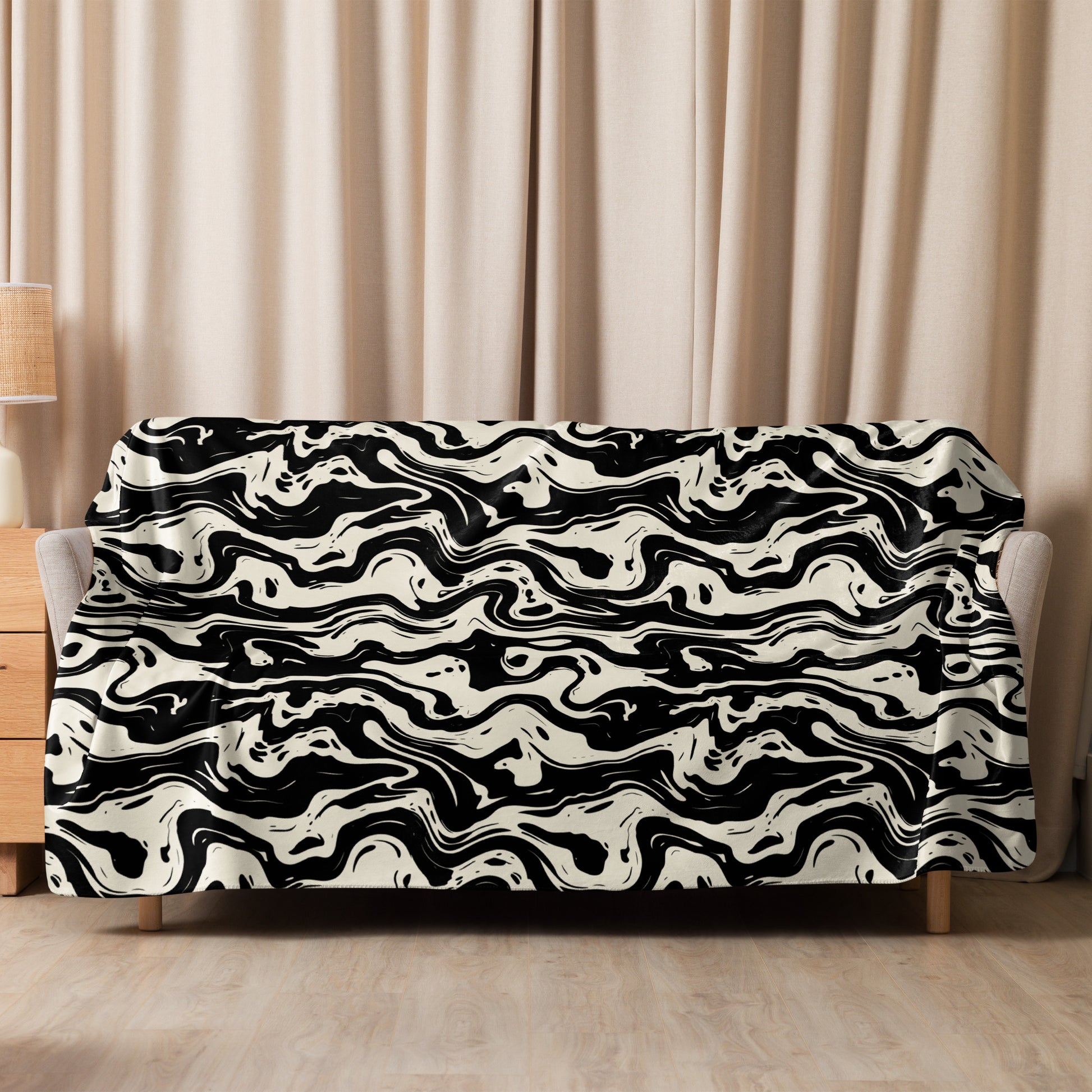 Cozy sherpa blanket with black and cream marbled design draped over a sofa in a warm, inviting room setting.