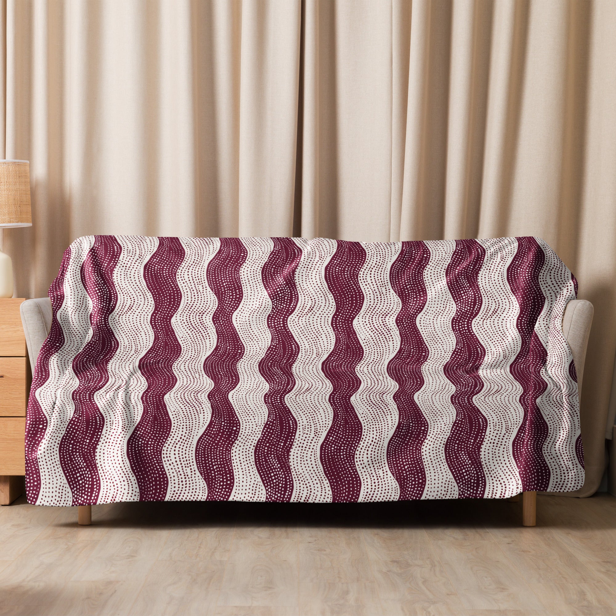 Burgundy wave patterned sherpa blanket draped over a couch, featuring soft and cozy knitted texture ideal for winter comfort.