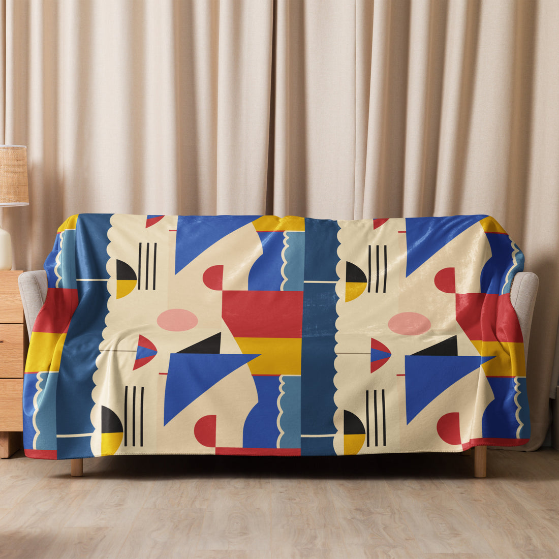 Sherpa blanket draped on a couch with an abstract geometric pattern in blue, red, yellow, and cream colors, adding a modern artistic touch.