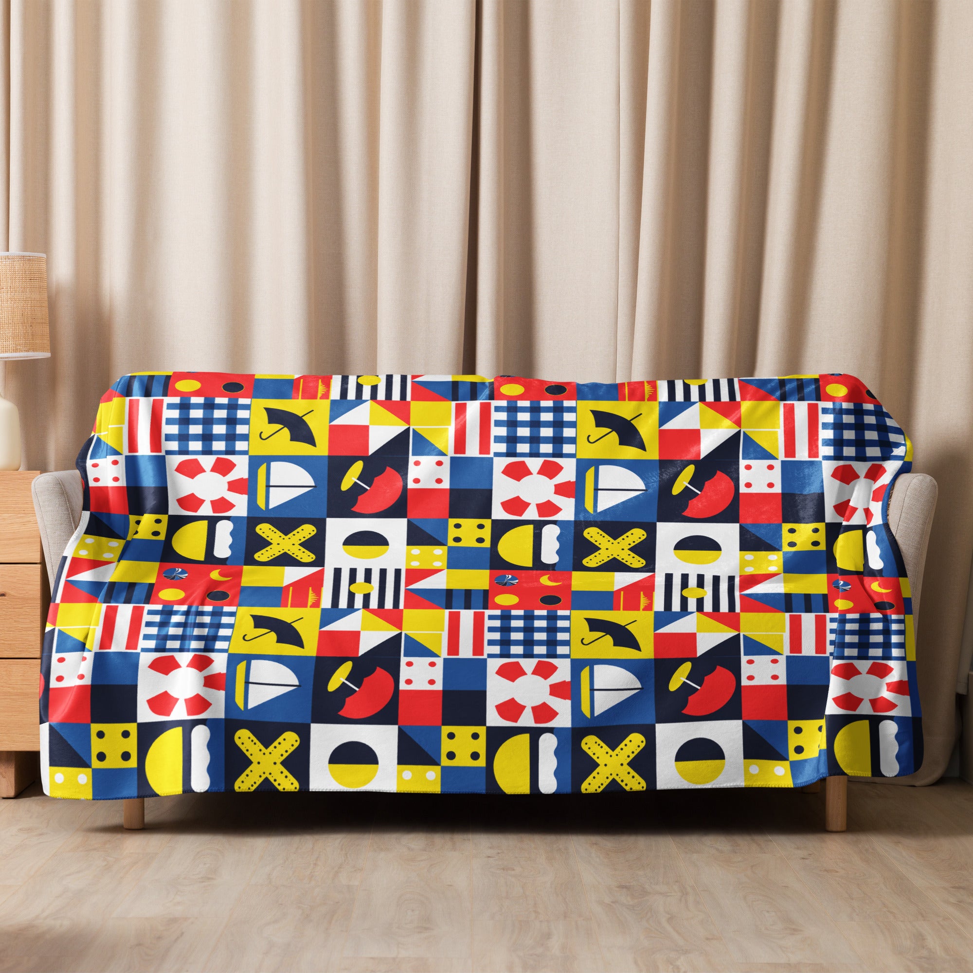 Sherpa blanket with vibrant nautical-themed pattern in red, blue, yellow, and white, styled in a cozy living room.