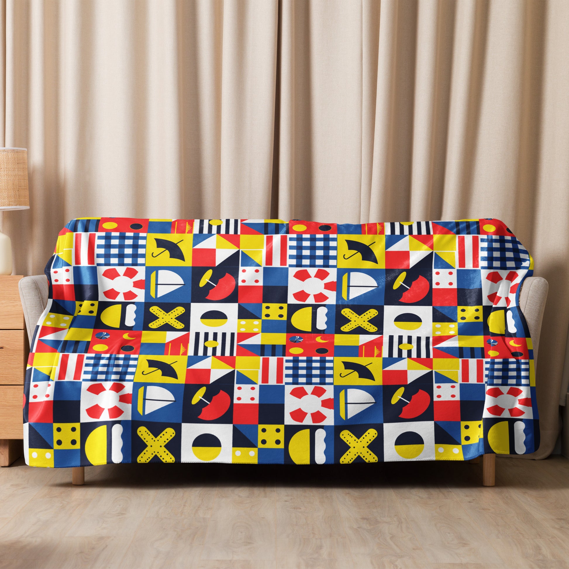 Sherpa blanket with vibrant nautical-themed pattern in red, blue, yellow, and white, styled in a cozy living room.