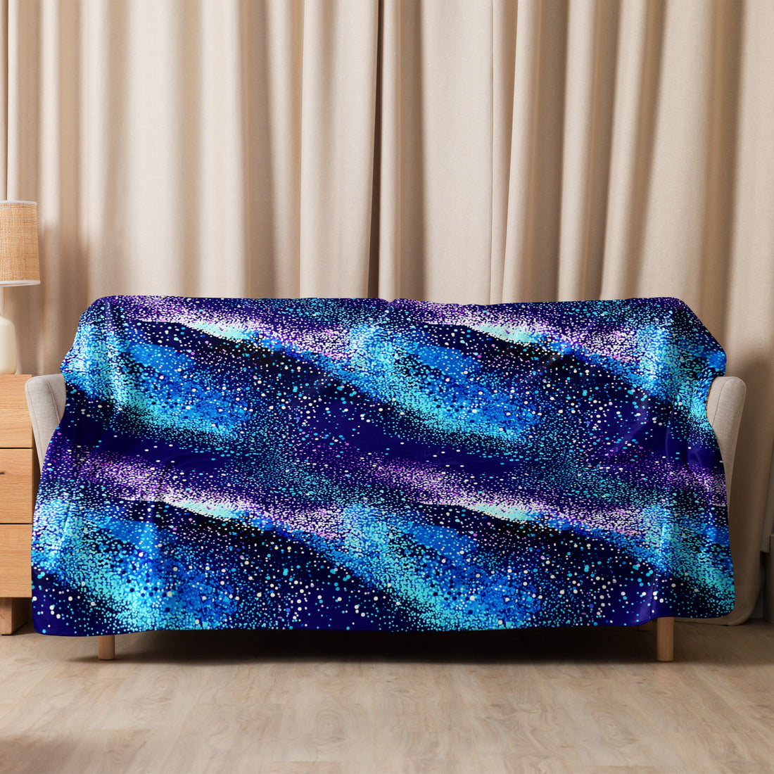 Starry Night Sherpa Blanket draped over sofa showing galaxy-inspired design with blue and purple hues, evoking a cosmic winter night.