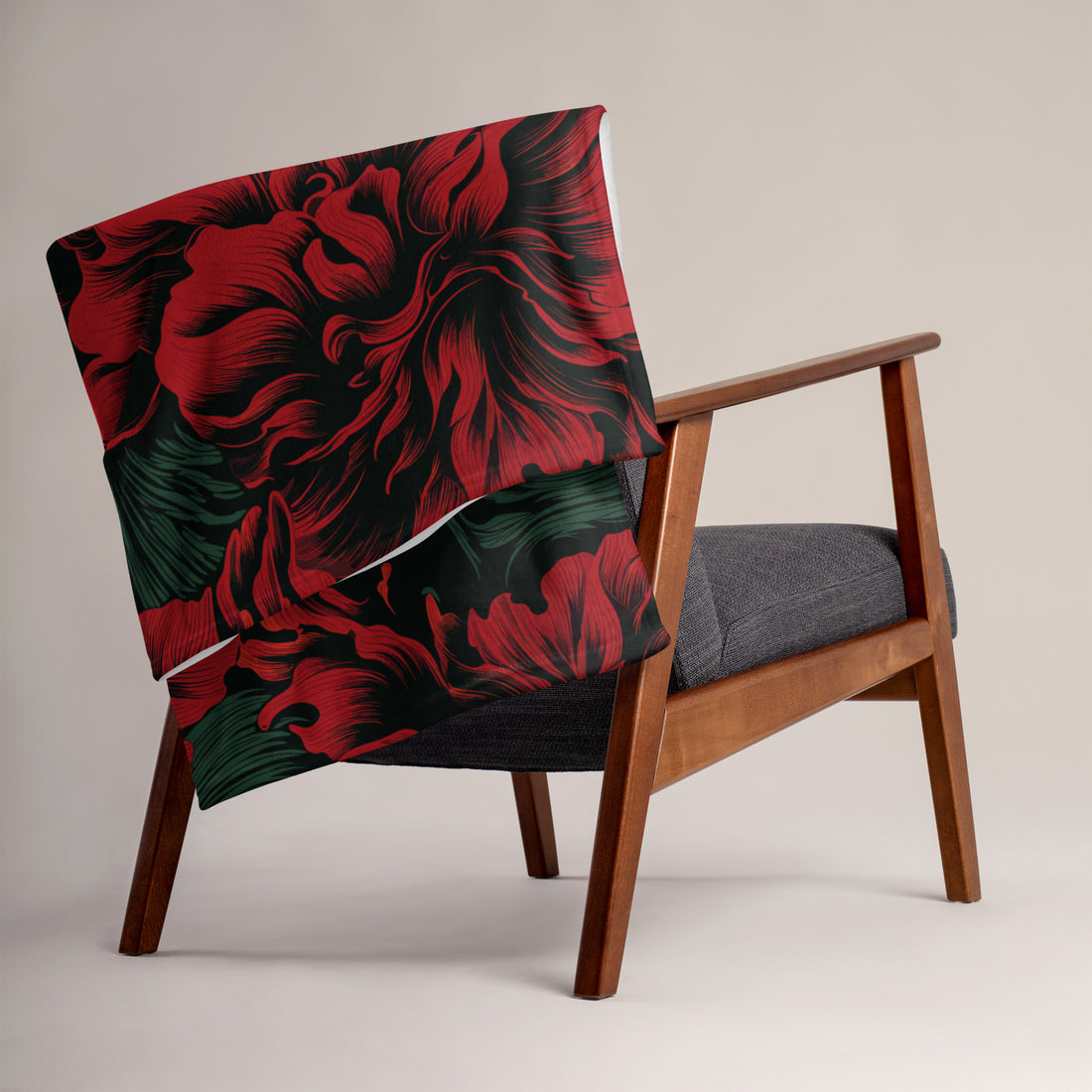 Exquisite floral silk touch throw blanket featuring vibrant red flowers and green foliage on a black background draped over a modern chair.