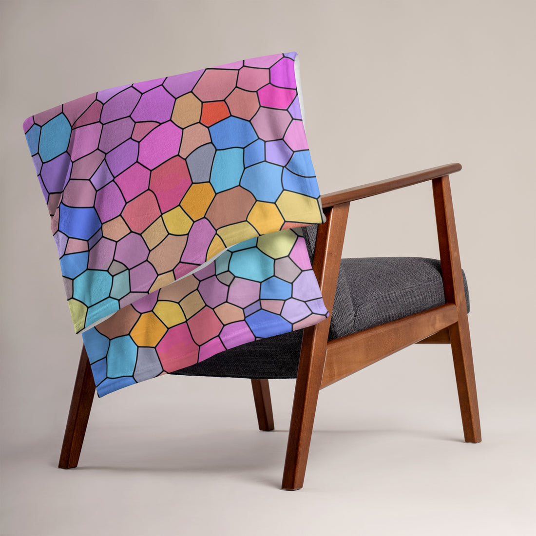 Vibrant geometric silk touch throw blanket in bright pastel colors draped over a wooden armchair.