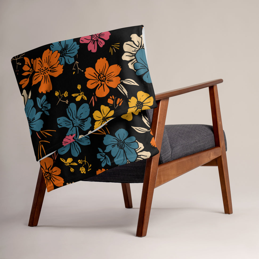 Vibrant floral silk touch throw blanket displayed on a modern armchair, featuring colorful flowers on a black background.