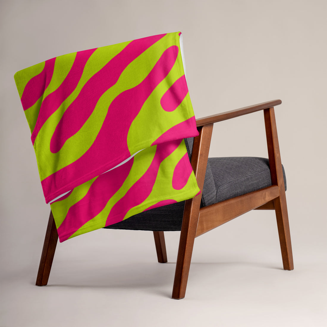 Vibrant pink and green silk touch throw blanket draped over a chair, showcasing bold design.