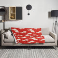 Red and cream throw blanket with cloud motif design, displayed on a modern couch in a stylish living room setting.