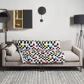 Geometric Pop Throw Blanket with black, white, yellow, red, and blue checkered design draped over a sofa.