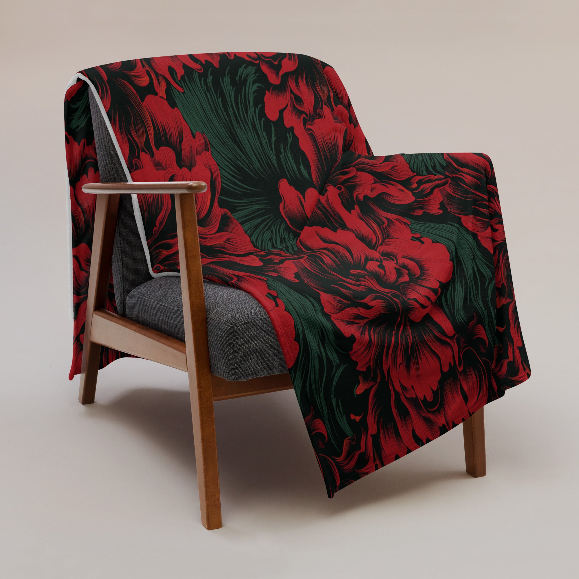 Exquisite floral silk touch throw blanket featuring vibrant red flowers and green foliage on a black background draped over a modern chair.