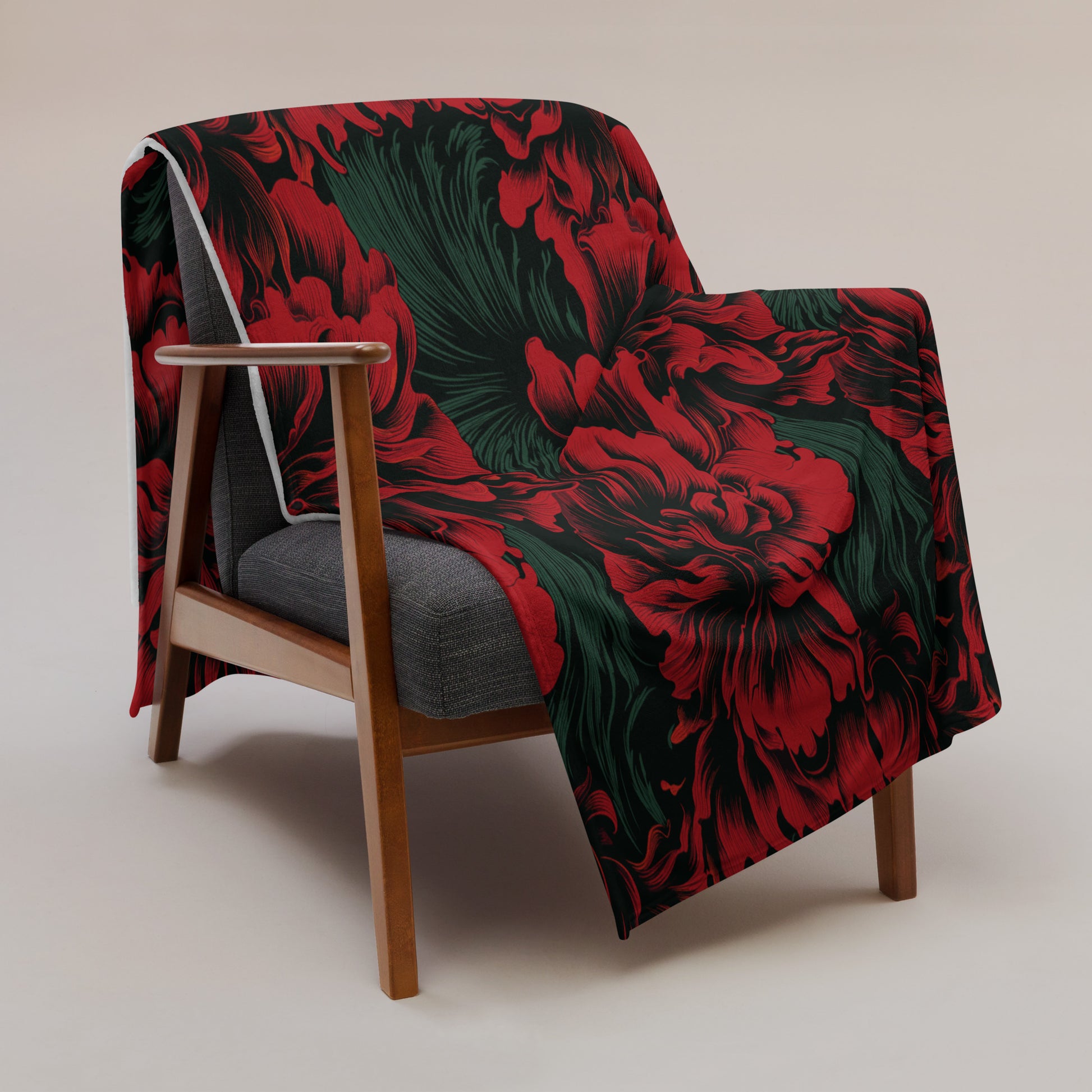 Exquisite floral silk touch throw blanket featuring vibrant red flowers and green foliage on a black background draped over a modern chair.