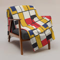 Chic geometric throw blanket in vibrant colors draped over a chair.