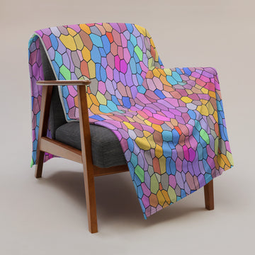 Vibrant geometric silk touch throw blanket in bright pastel colors draped over a wooden armchair.