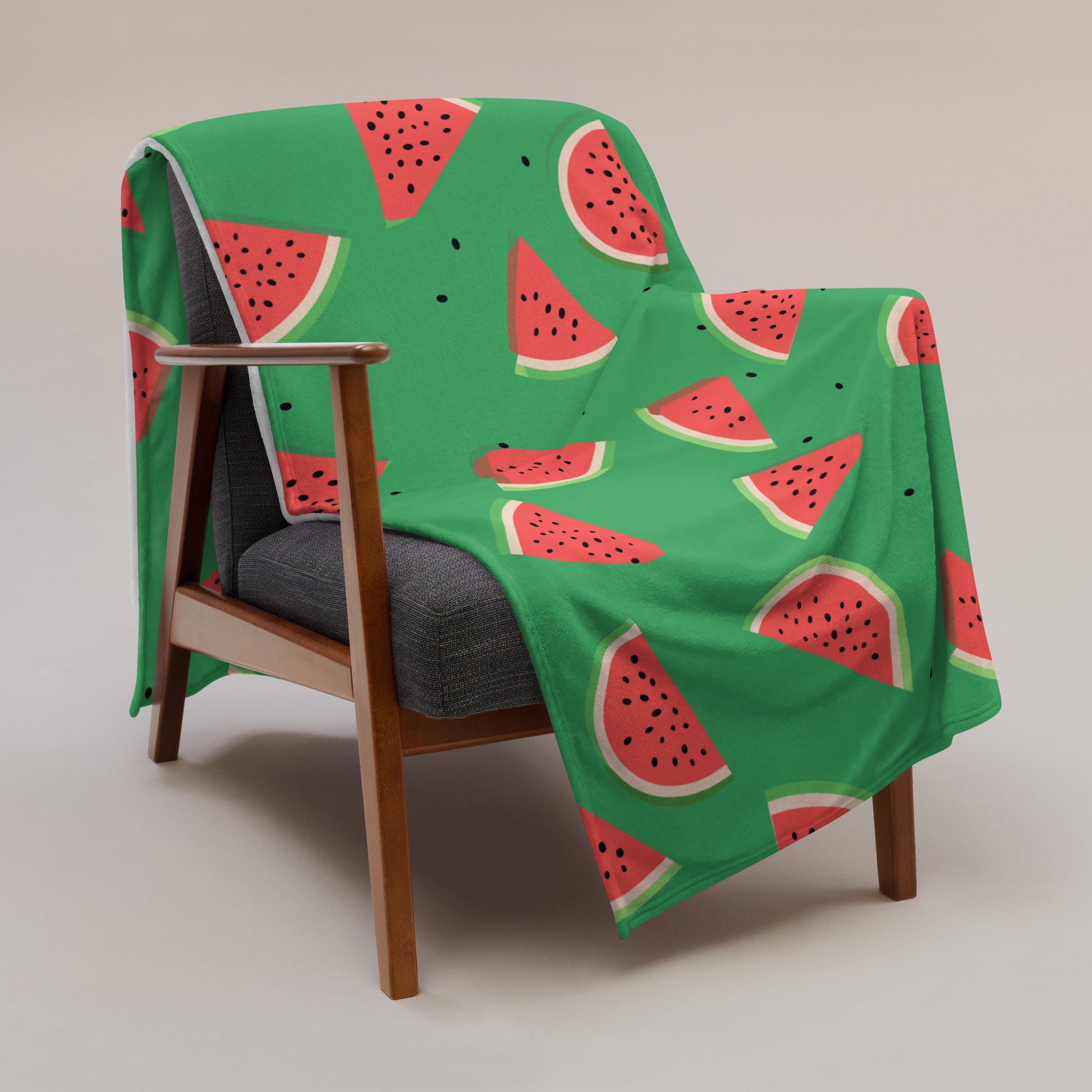 Vibrant watermelon print throw blanket draped over a chair, featuring a bright green background and slices of watermelon.