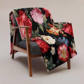 Luxurious floral silk touch throw blanket with vibrant flowers on a black background, draped over an armchair.