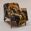 Leopard print silk touch throw blanket draped over a chair, featuring vibrant colors and a luxurious design.