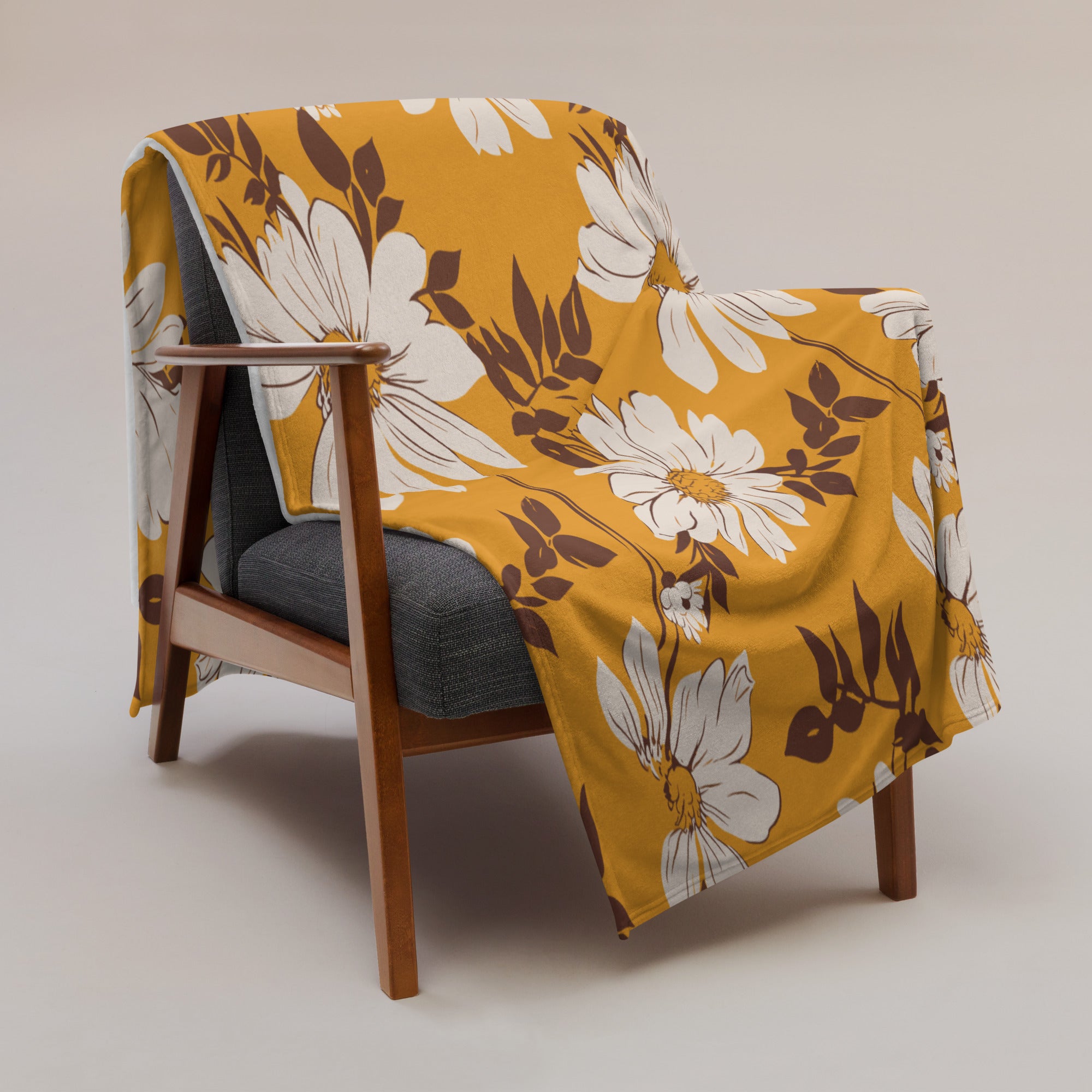 Floral silk touch throw blanket on a chair, featuring a mustard background with white and brown flowers.