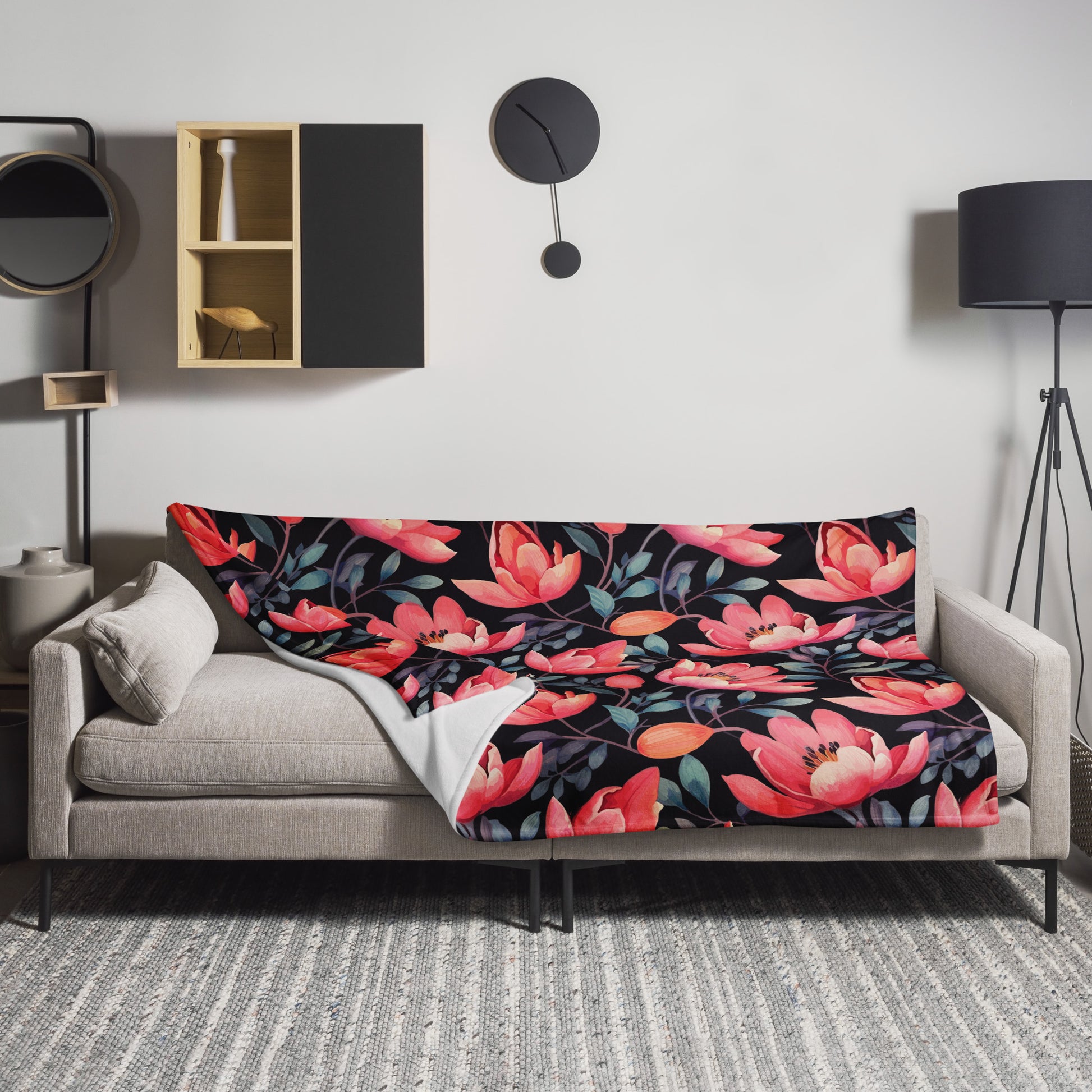 Throw blanket with vibrant coral magnolia flowers on a black background, draped over a sofa in a modern living room setting.