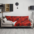 Scarlet red hibiscus floral knitted throw blanket draped over a sofa with striking floral design ideal for winter decor.