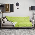 Green throw blanket with white cloud patterns draped over a couch in a modern living room.