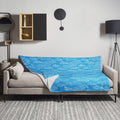 Blue throw blanket with white cloud patterns draped over a sofa in a modern living room setting.