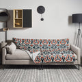 Tribal pattern throw blanket with orange, blue, and cream design on a couch.