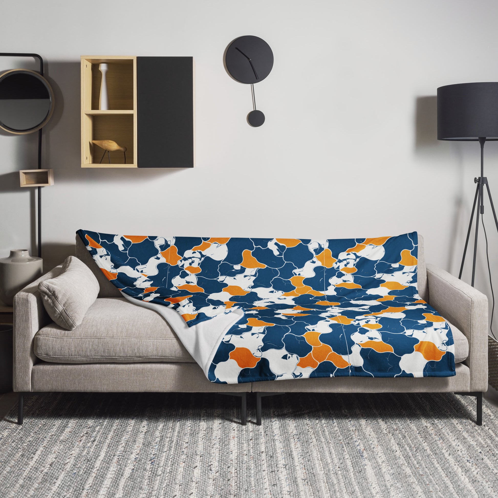 Abstract autumn camouflage throw blanket in blue, orange, and white with knitted design, draped over a sofa