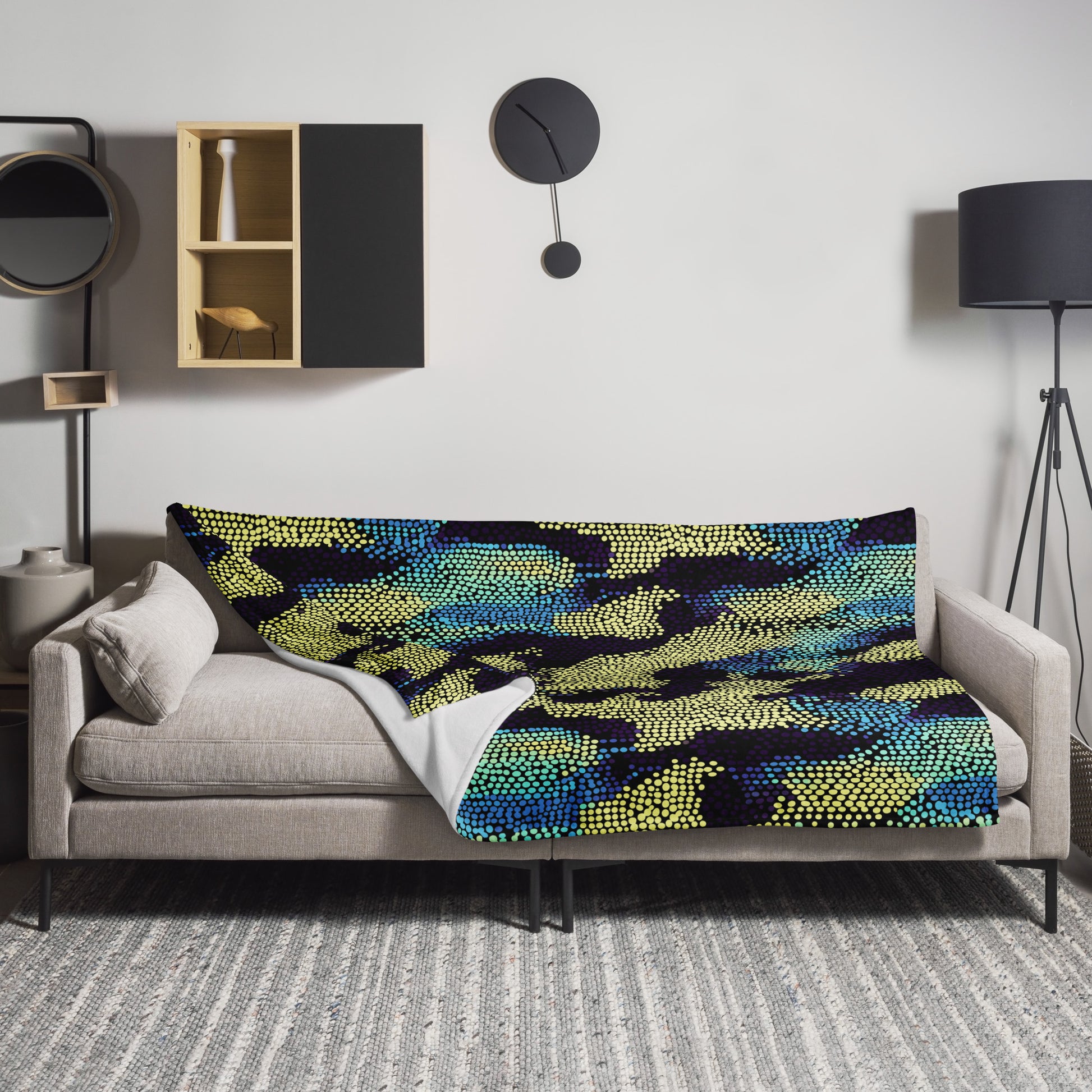 Knitted throw blanket with Nightfall Mosaic design in deep blues, greens, and yellows draped over a modern sofa.